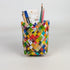 Colorful woven pencil holder with stationery items on a white background